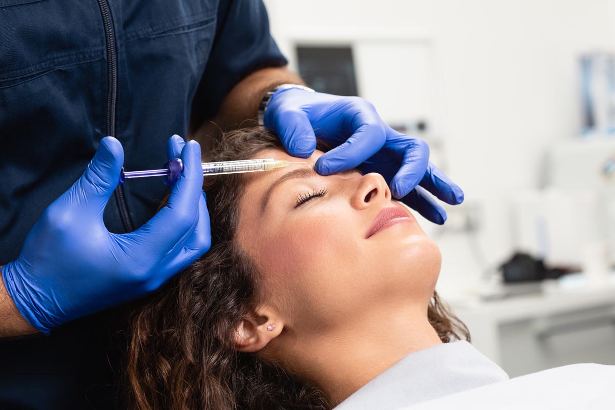 Close up of beautician expert's hands injecting Xeomin in a patient.