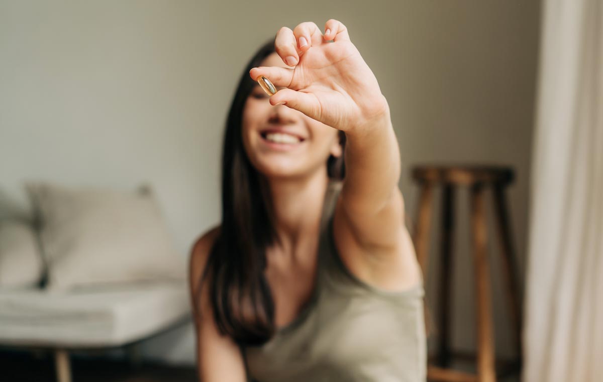 Happy healthy woman holding out a pill in her hand.