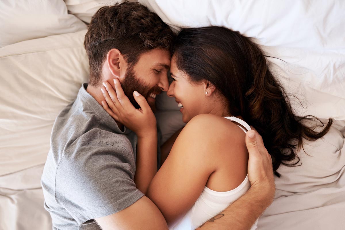 Happy couple hugging in bed.