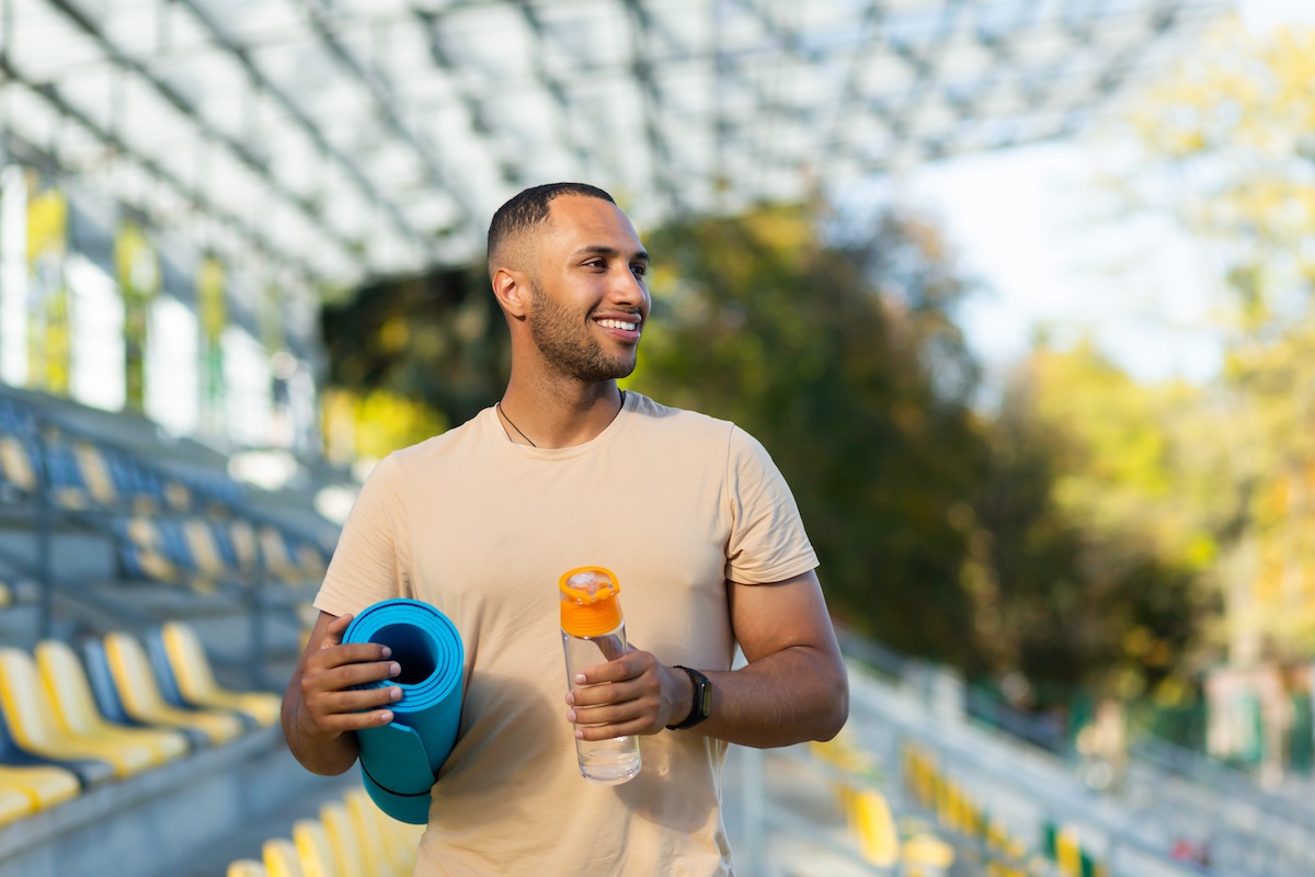 Portrait of sportsman with bottle of water, man resting walking stadium for training, young athlete yoga and fitness trainer.