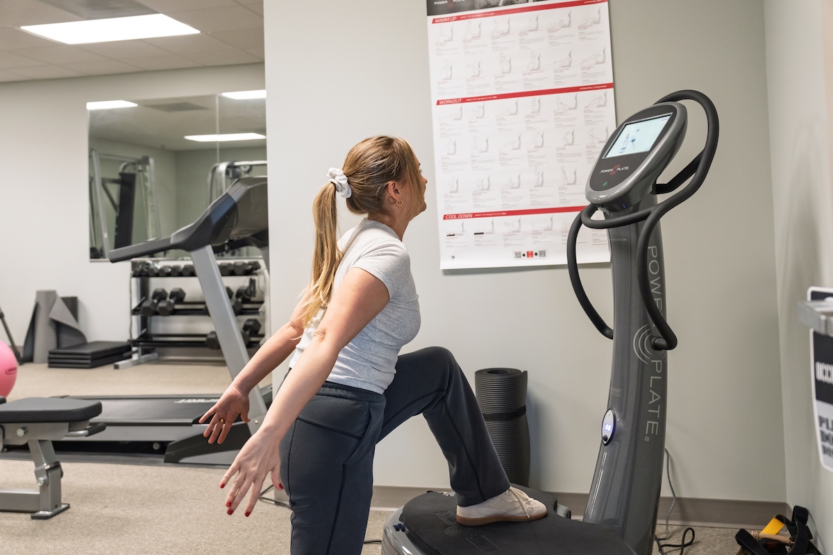 Patient using Power Plate vibration therapy for muscle recovery